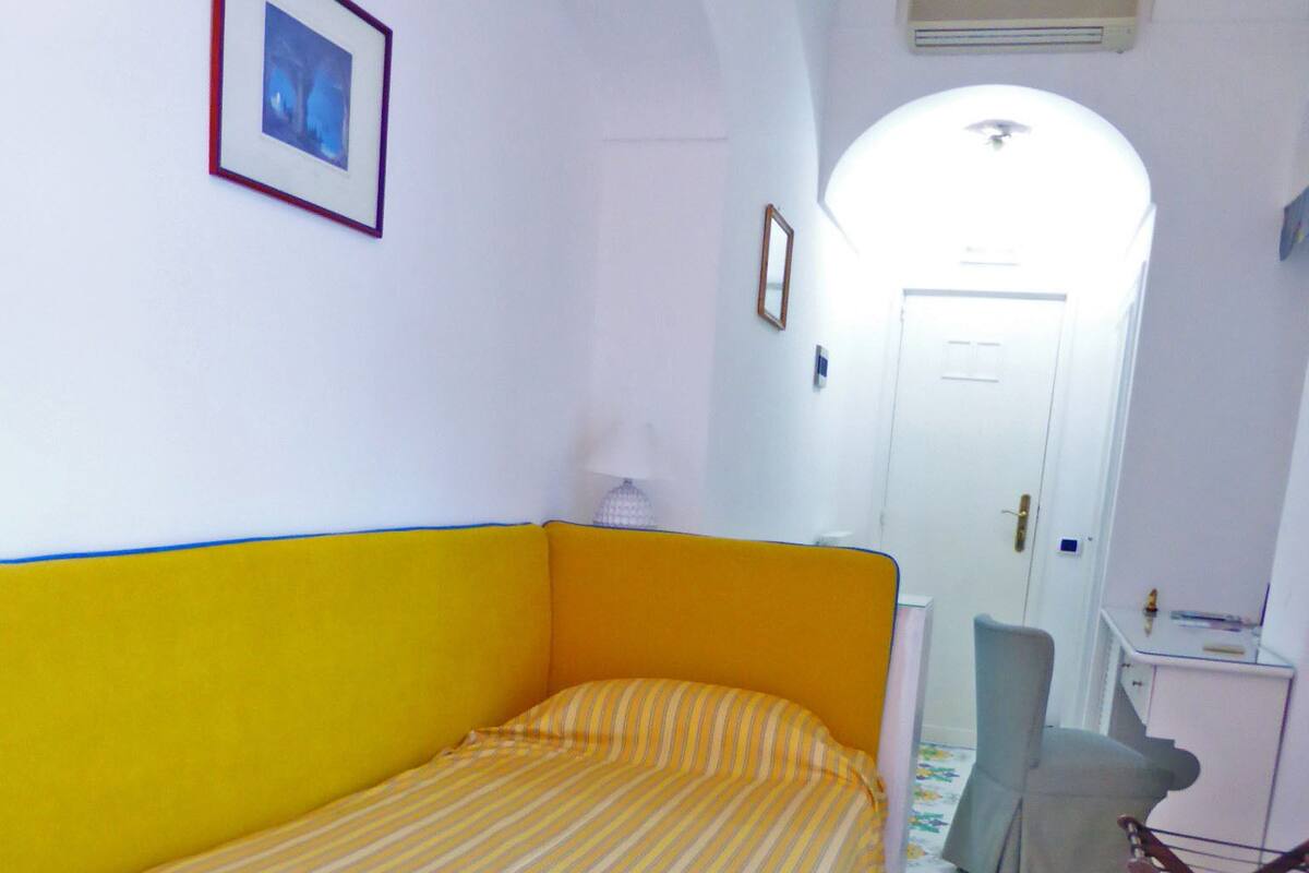 A room with a bed, a chair, a small table, and a door.