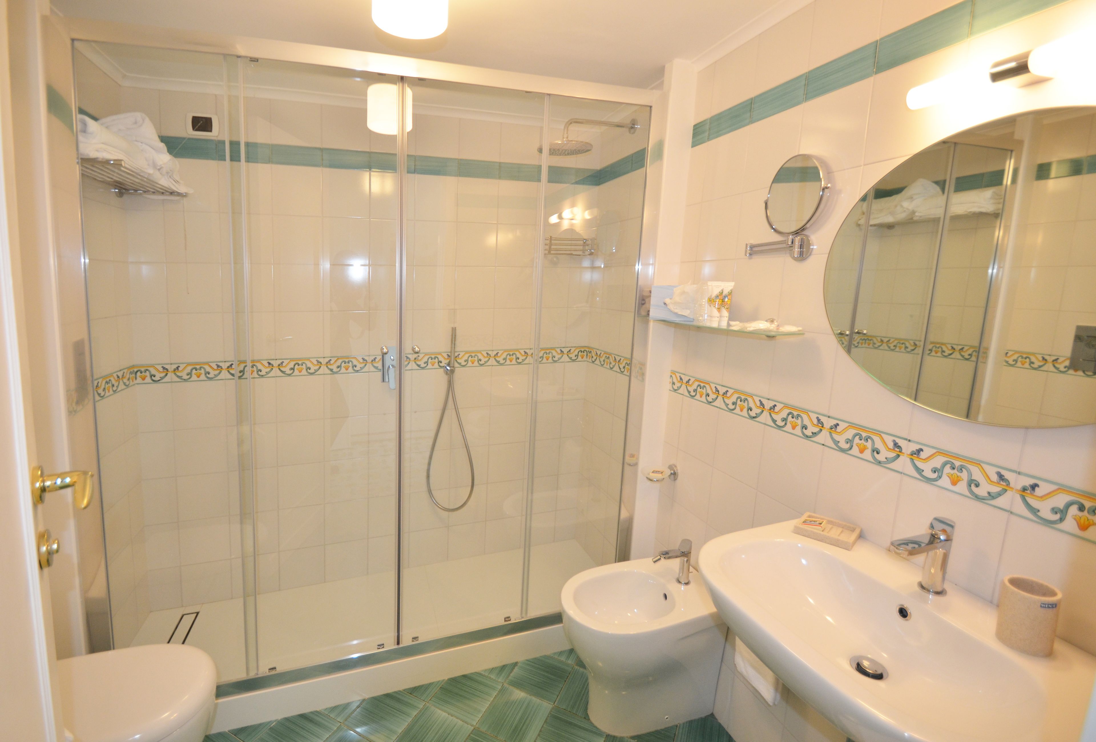 Ein Badezimmer mit einer Duschkabine, einer Toilette, einem Bidet und einem Waschbecken mit Spiegel darüber.