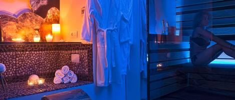 A spa area with a stone wall, candles, and towels.
