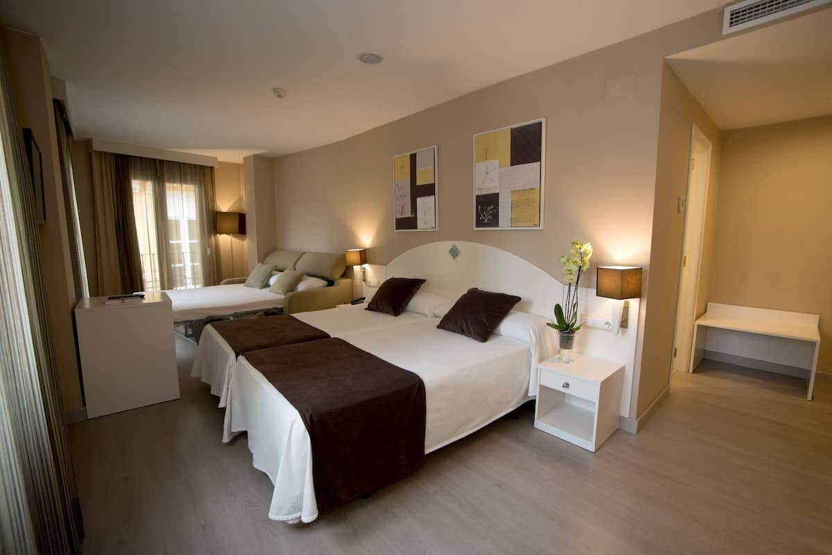 Una habitación de hotel con una cama grande, dos mesitas de noche, un escritorio y una silla.