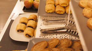 Een buffet met diverse soorten eten, zoals fruit, gebak en brood.