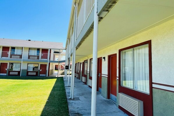Una hilera de habitaciones de motel con un paseo central, cada una con ventana y puerta.
