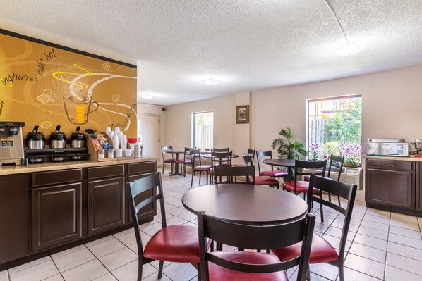 A restaurant with a counter, multiple tables, and chairs. - Red Roof Inn Hardeeville (Hardeeville)