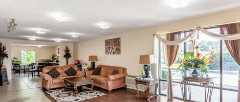 A spacious living room with a brown leather sofa, a coffee table, and a dining area in the background.