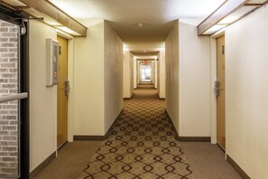 Un pasillo de hotel con pisos alfombrados, puertas a ambos lados y un diseño de alfombra estampado.