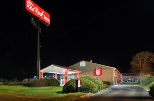 Un hotel Red Roof Inn con un letrero llamativo, un estacionamiento y jardines bien cuidados.