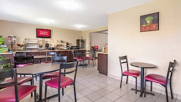 A restaurant with multiple tables and chairs, a kitchen area, and a sign indicating free Wi-Fi availability.