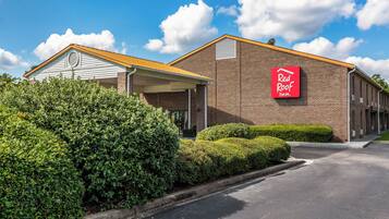 A Red Roof Inn with a brick facade, a covered parking area, and well-maintained landscaping.