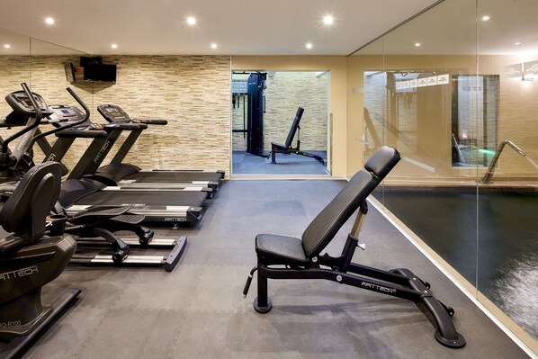 Un gimnasio con cintas de correr, una banca y una plataforma para pesas.