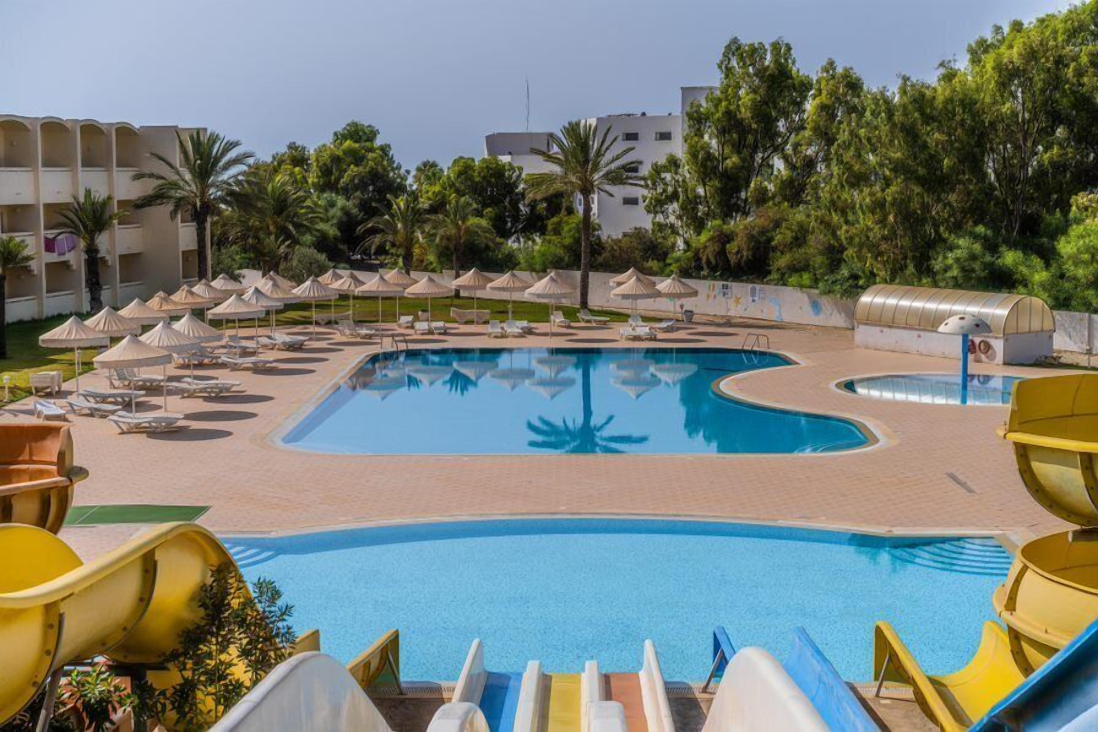 A swimming pool with multiple lanes, lounge chairs, and umbrellas.