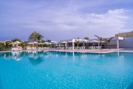 Una piscina techada, una piscina al aire libre, sombrillas