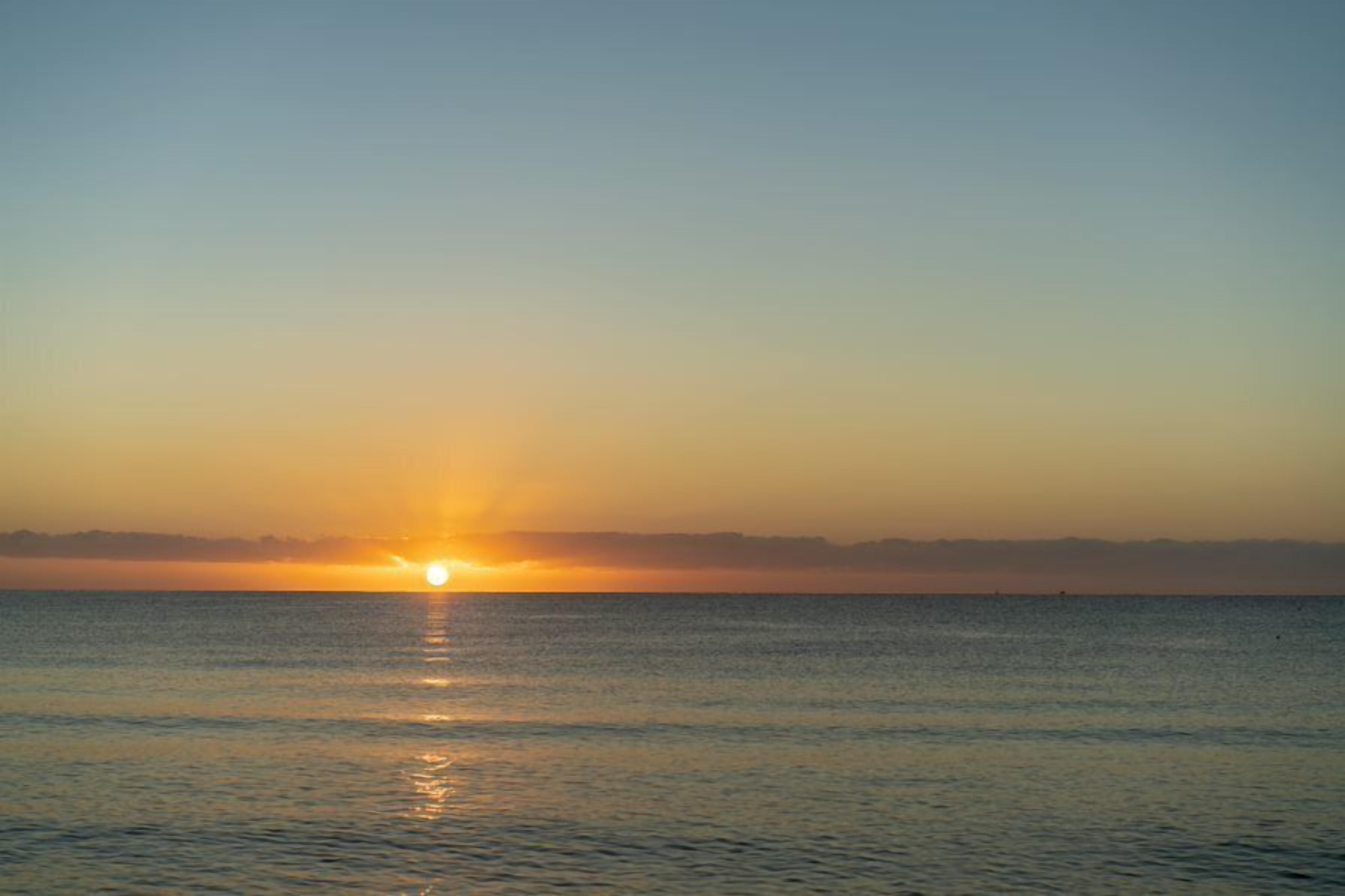 A sunset over a calm sea with a clear horizon.