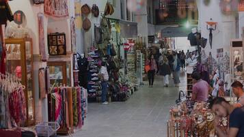 A bustling indoor market with various stalls selling textiles, bags, and accessories.