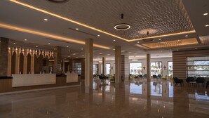 Eine geräumige Lobby mit poliertem Marmorboden, einem Empfangsbereich und modernen Leuchten.