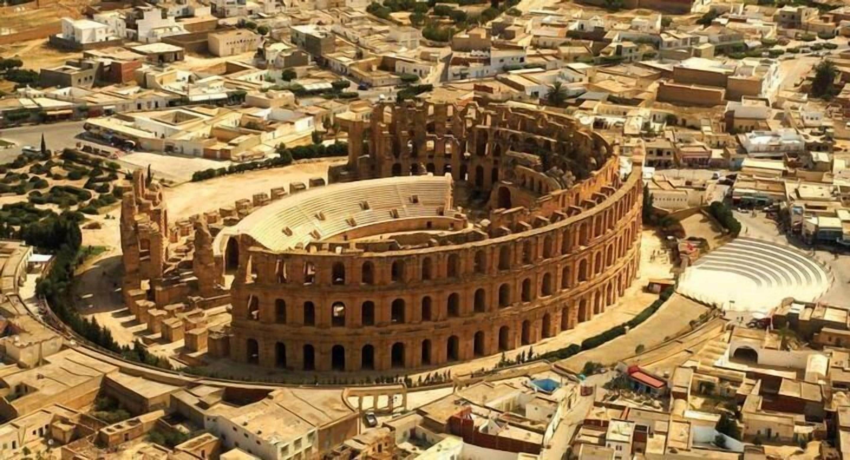 A large, circular ancient amphitheater surrounded by a dense urban area with various buildings.