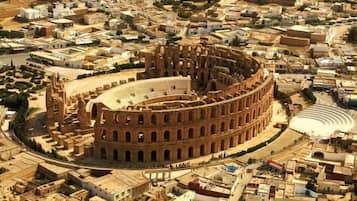 A large, circular ancient amphitheater surrounded by a dense urban area with various buildings.