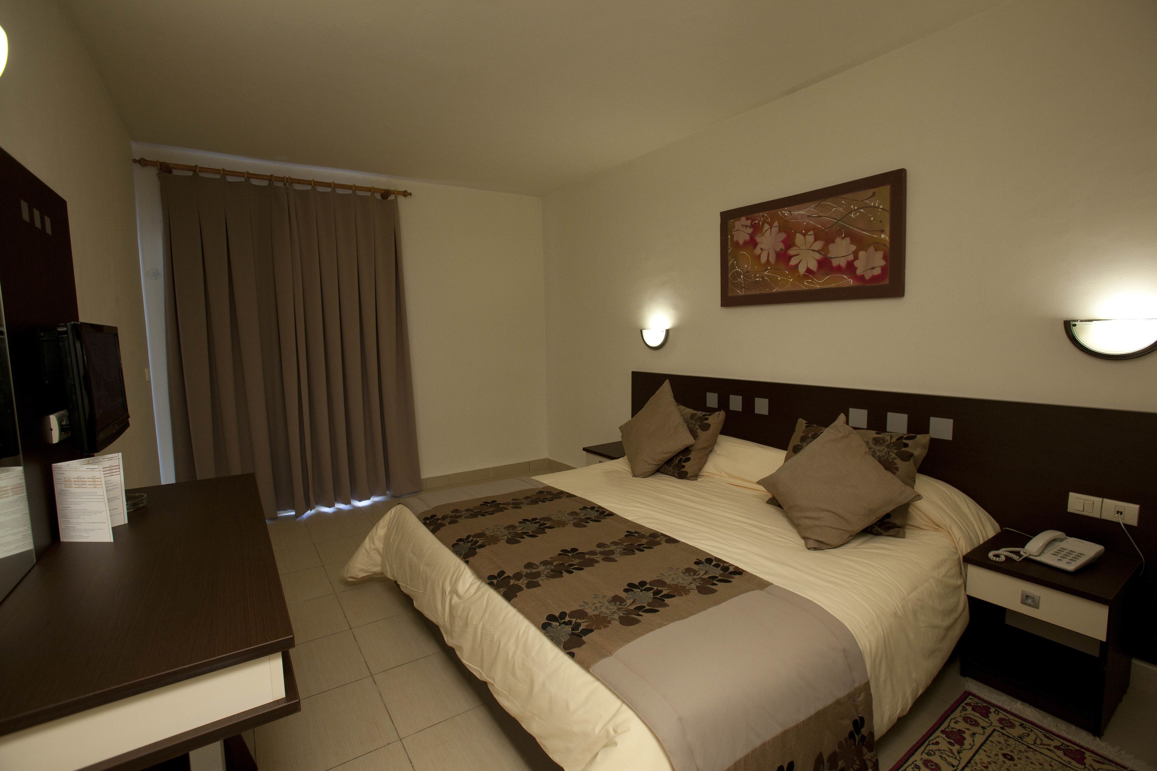 Una habitación de hotel con cama, mesita de noche y escritorio.