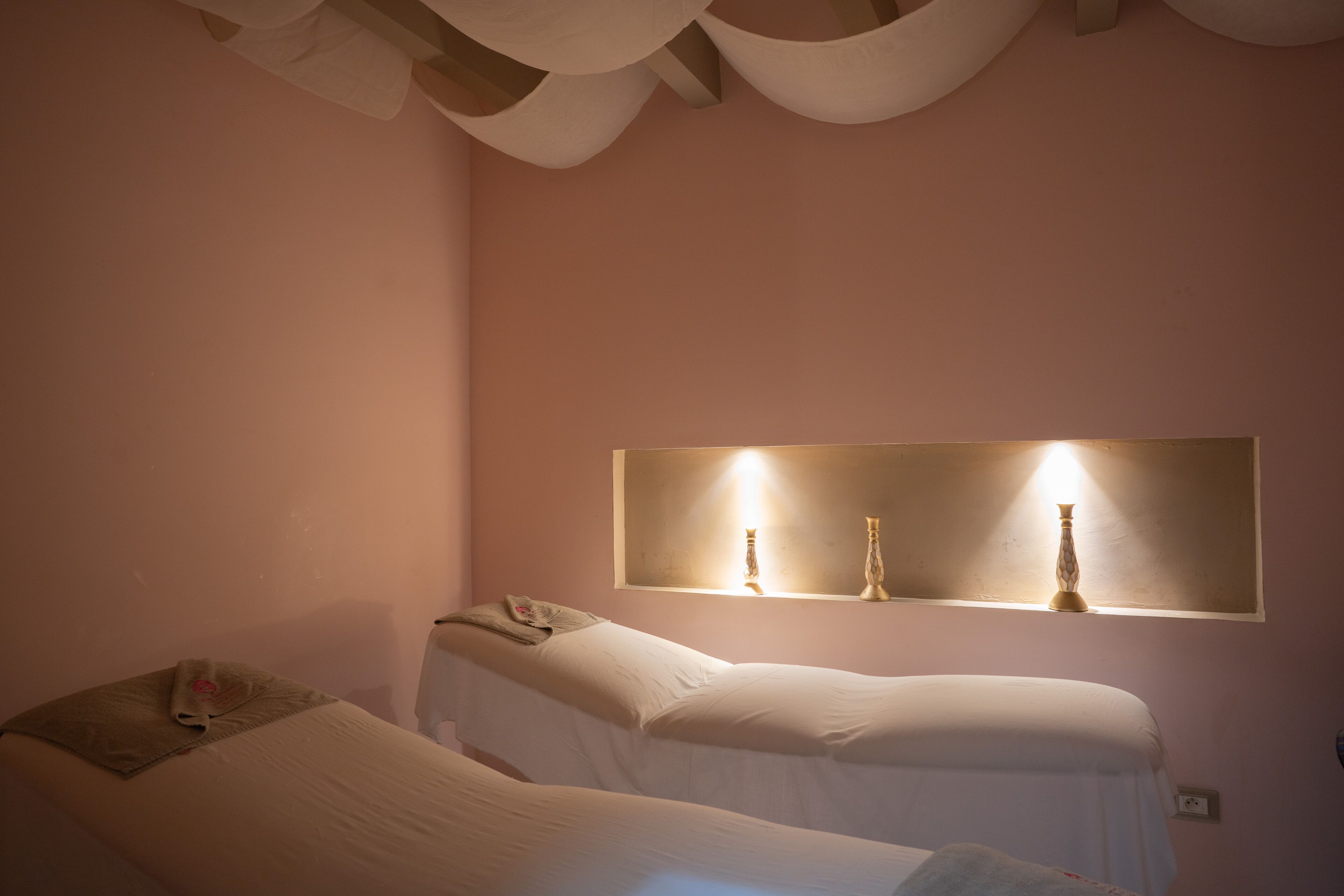 Camera d'albergo con due letti, un grande specchio e un lampadario a parete.