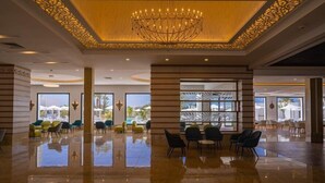 Eine großzügige Lobby mit poliertem Boden, einem großen Chandelier und Sitzbereichen mit Blick ins Freie.
