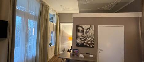 A modern living room with a wooden floor, a dining table, a sofa, and a painting on the wall.