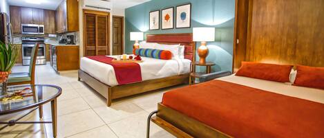A hotel room with two beds, a kitchenette, and a dining area.