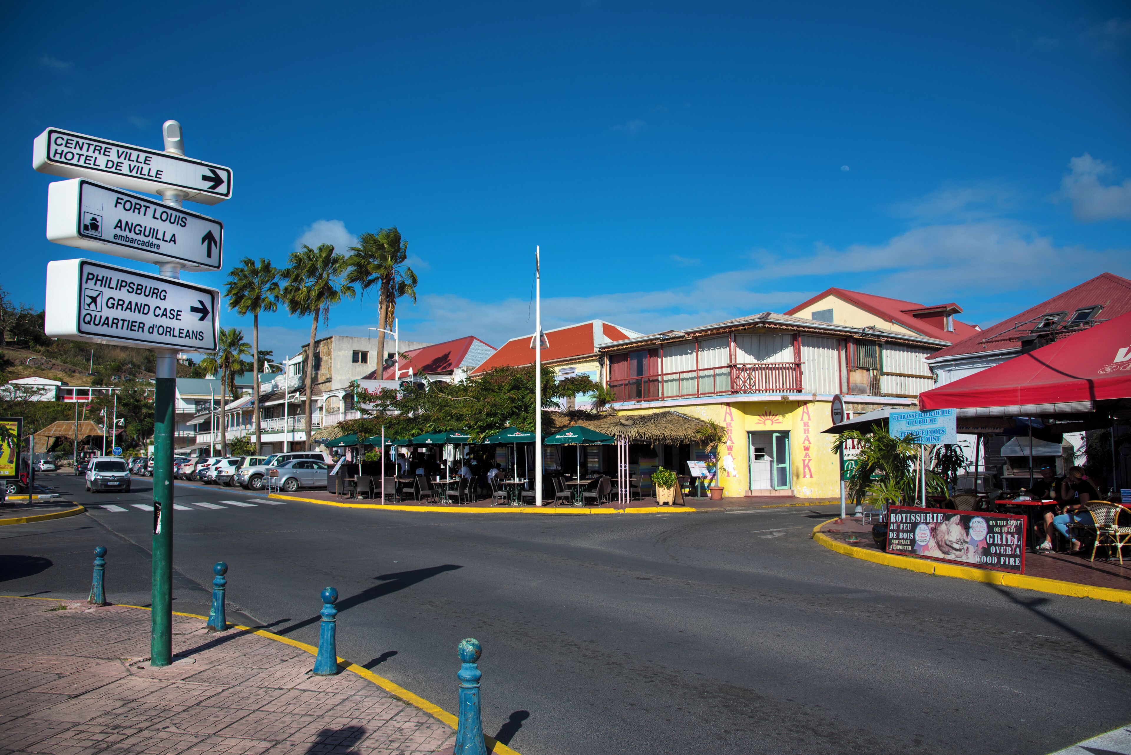 A street with directional signs, a restaurant, and a building with a red roof.