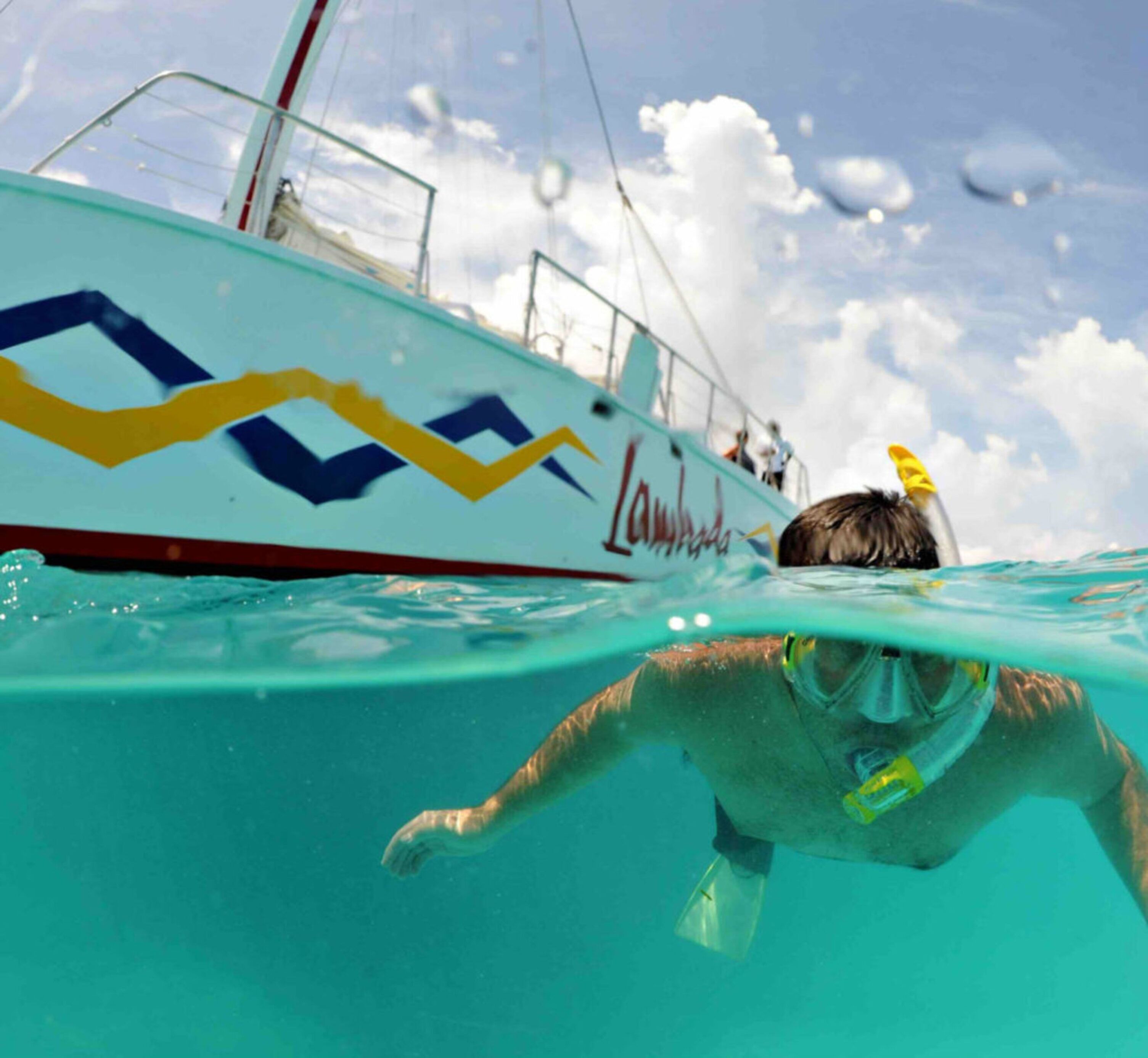 A person snorkeling underwater with a boat in the background.