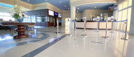 A hotel lobby with a reception desk, a blue and white color scheme, and a large vase of white flowers.
