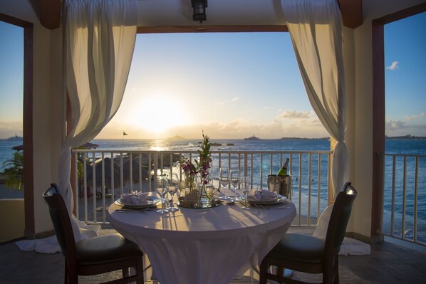 A table set for two with a view of the sea and mountains at sunset.