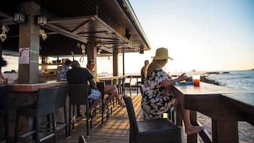 Un restaurante frente al mar con terraza al aire libre, una cubierta de madera y vistas al océano.