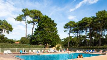 Een buitenzwembad, parasols bij het zwembad en ligstoelen