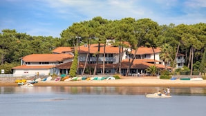 A beachfront property with multiple buildings, a sandy beach, and a calm lake. - SOWELL Family Pignada Plage (Soustons)