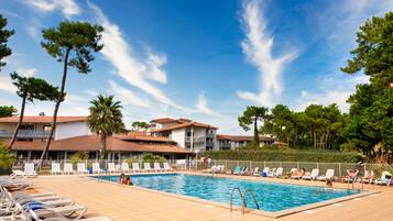 Een buitenzwembad, parasols bij het zwembad en ligstoelen