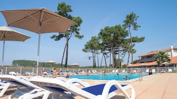 Una piscina al aire libre, sombrillas, sillones reclinables de piscina