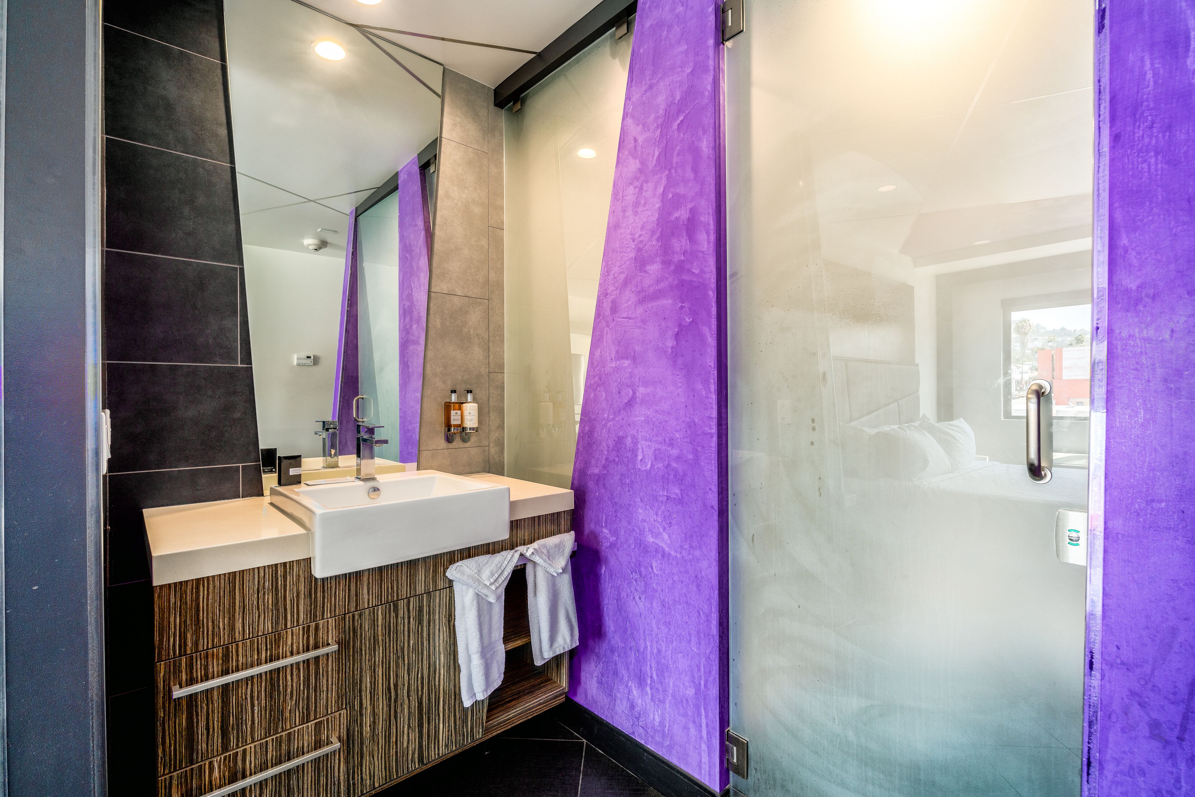 Un baño moderno con un espejo grande, dos lavamanos y una zona de ducha.