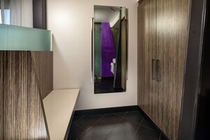 Een moderne badkamer met een douchecabine van glas, een houten wastafelmeubel en een vloer van zwarte tegels.