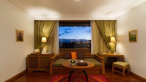 A room with a large window, a sofa, a small table, and two lamps.