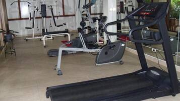 Un gimnasio con máquinas de cardio, incluyendo una cinta de correr y una elíptica, además de equipo para entrenamiento de fuerza.