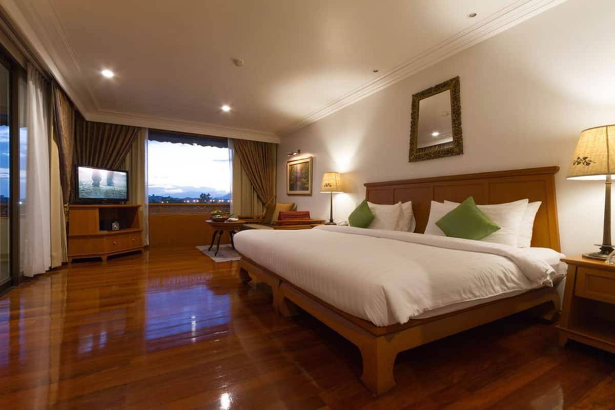 Habitación de hotel con una cama grande, televisor, escritorio y vistas a la ciudad.