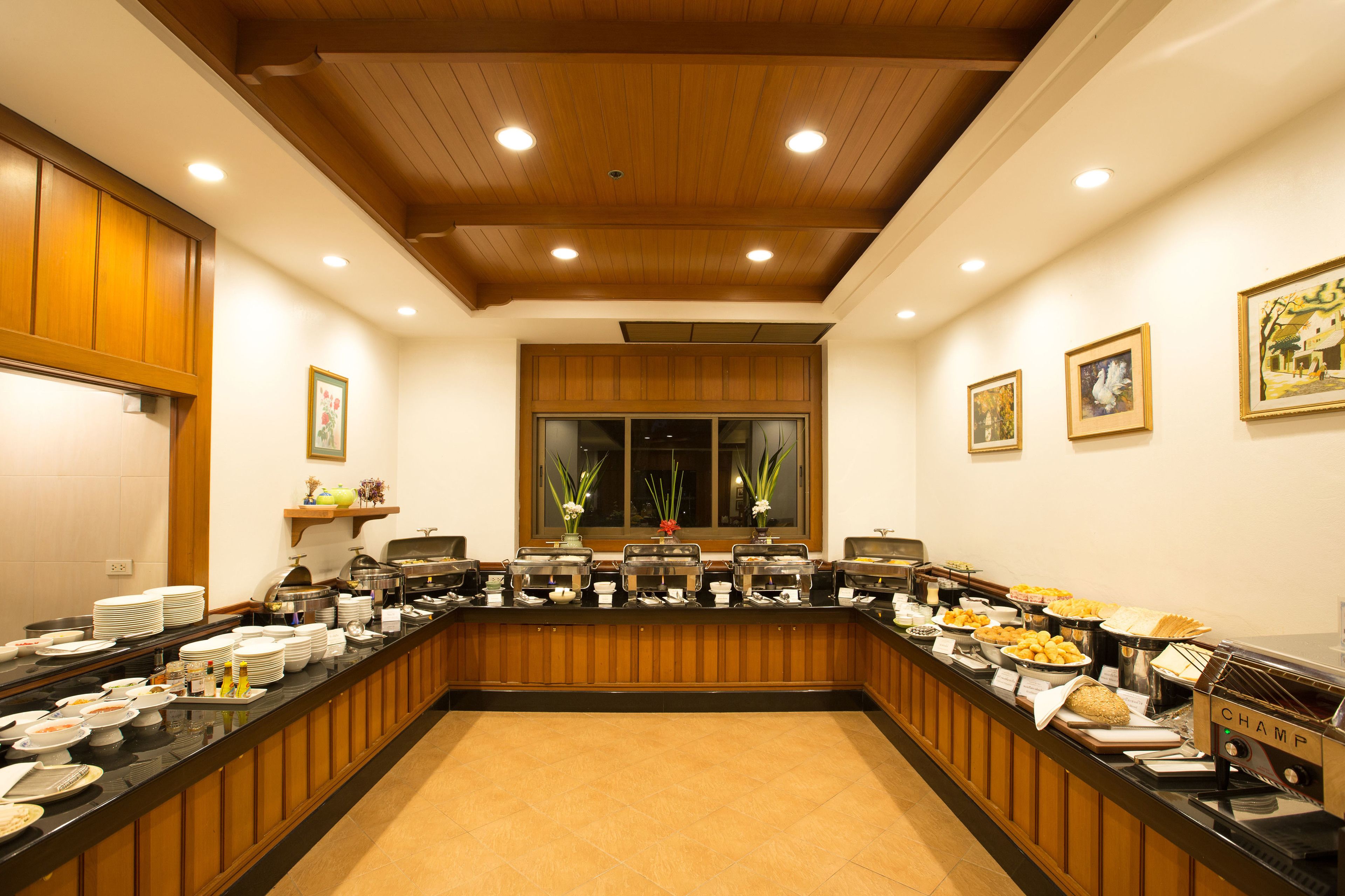 Disposição de buffet com vários pontos de comida, teto de madeira e obras de arte emolduradas nas paredes.