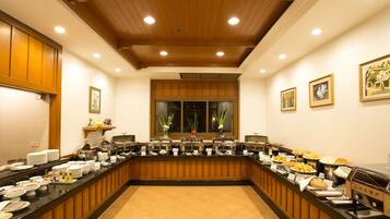 Disposição de buffet com vários pontos de comida, teto de madeira e obras de arte emolduradas nas paredes.