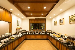 Disposição de buffet com vários pontos de comida, teto de madeira e obras de arte emolduradas nas paredes.