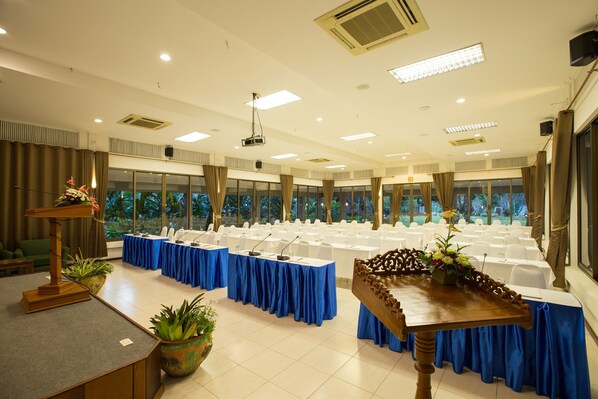 A conference room with tables set for a meeting, large windows, and a stage with a podium.