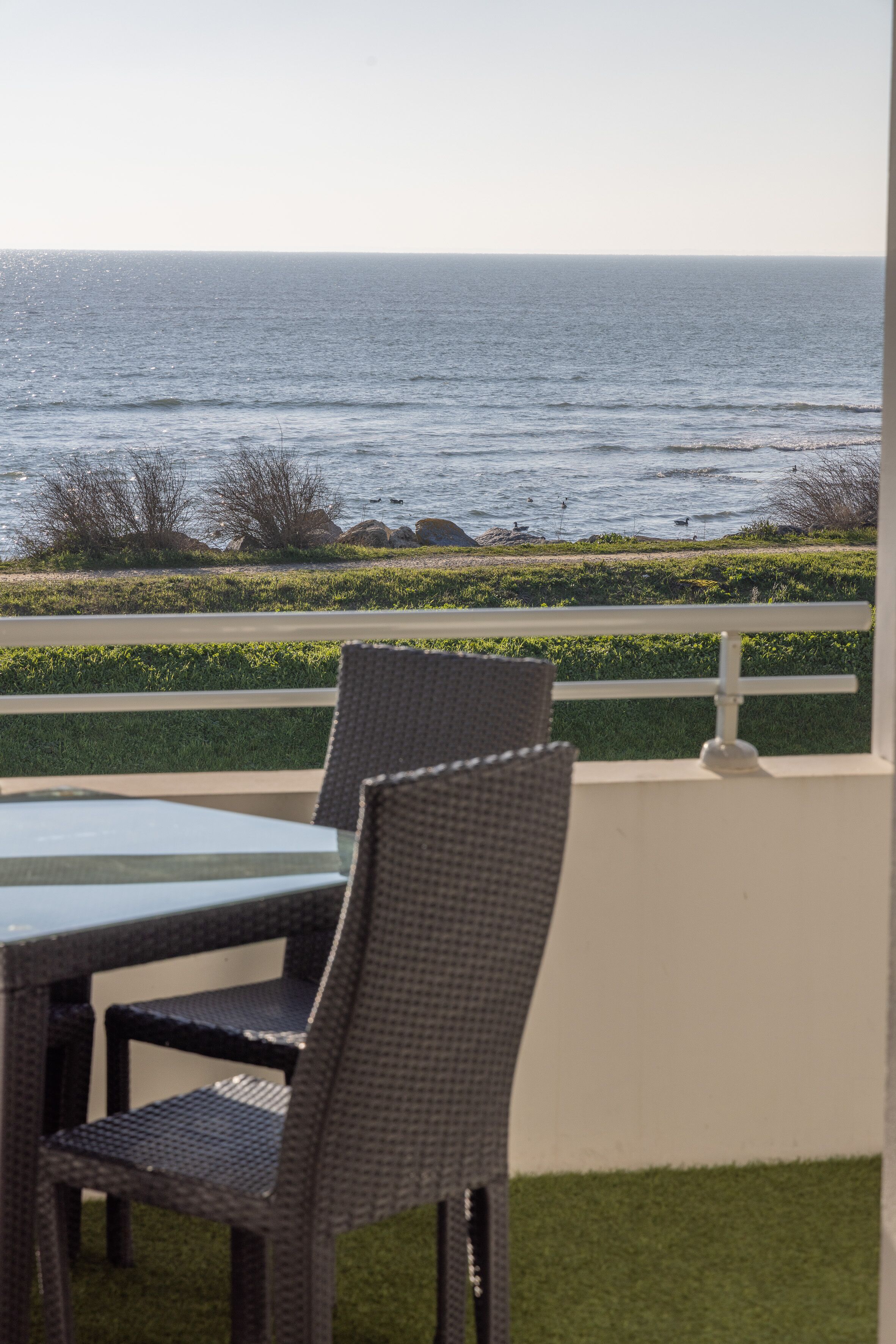 A patio with wicker chairs and a table overlooking the ocean.