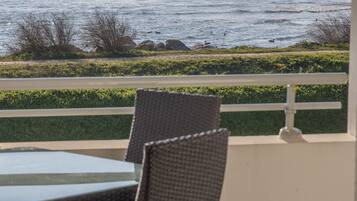 A patio with wicker chairs and a table overlooking the ocean.
