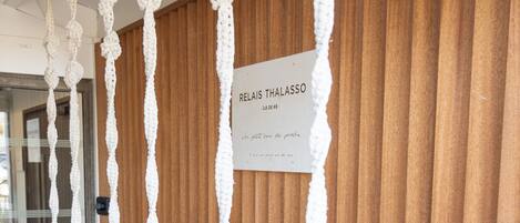 A series of macrame wall hangings with white cushions hanging from them, against a wooden wall.