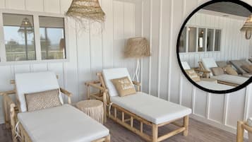 Relax in a comfortable outdoor lounge area with lounge chairs and a large mirror.