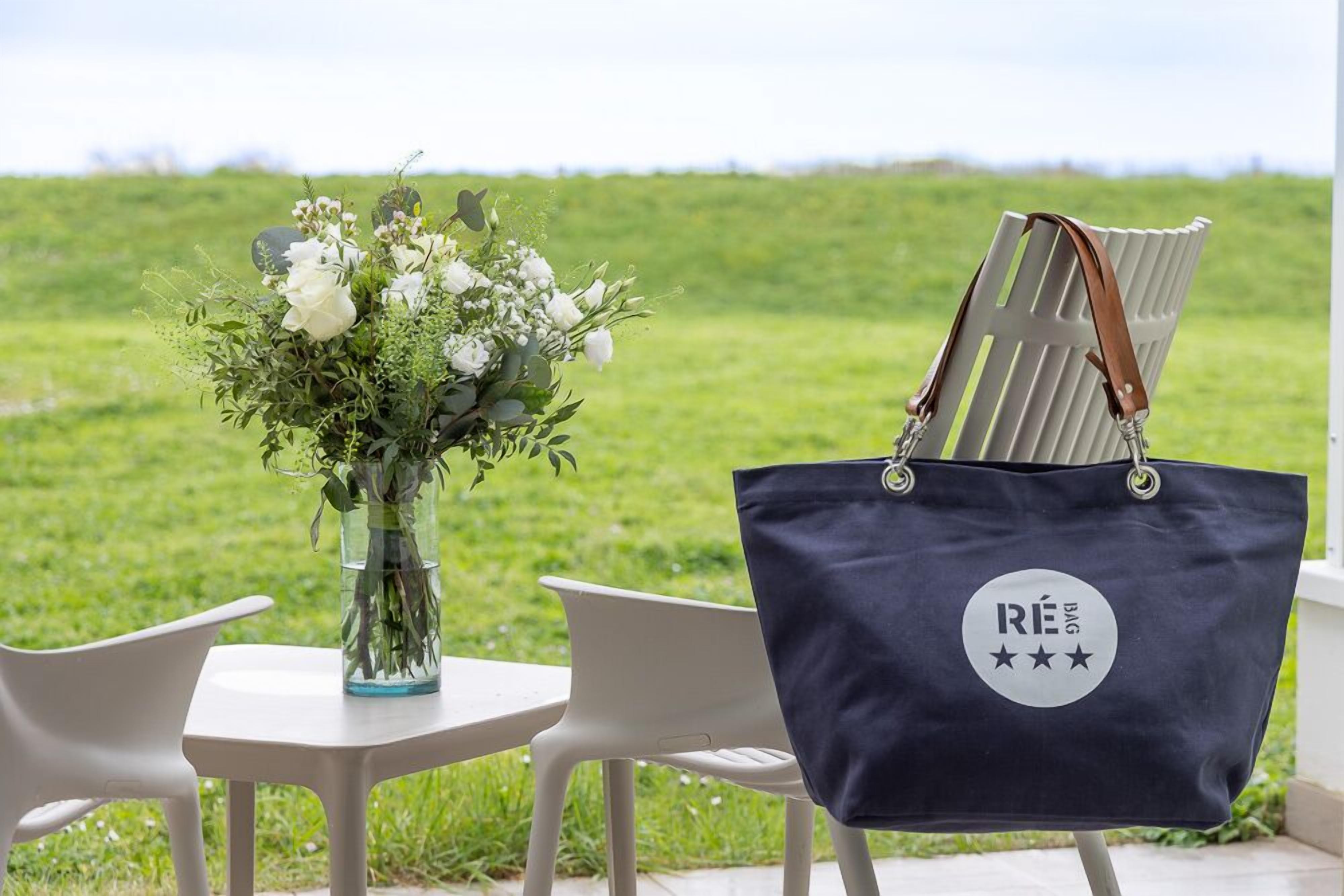 A table with a vase of flowers and a black tote bag with a logo.