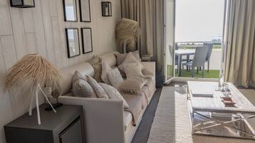 A modern living room with a sofa, coffee table, and a view of the outdoors.
