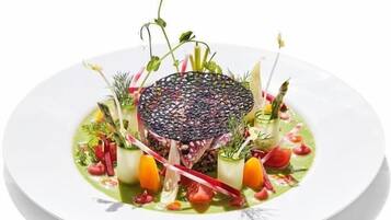 A white plate with a central dish surrounded by various vegetables and herbs.